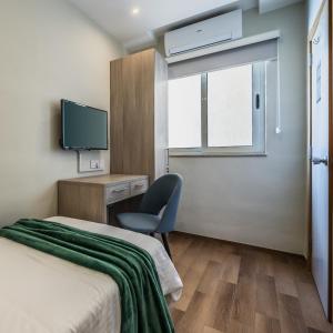 Schlafzimmer mit einem Bett, einem Schreibtisch und einem TV in der Unterkunft The Howard Hotel in Sliema