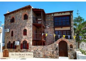 an old stone building with flags in front of it at Elounda Monastiri Cretan sea view house with pool in Epáno Eloúnda