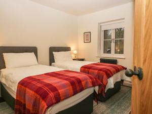 a bedroom with two beds and a window at Church How Cottage in Seascale