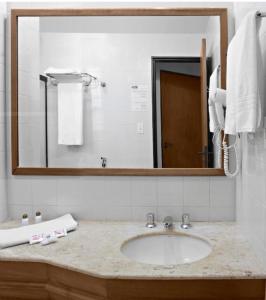 a bathroom with a sink and a large mirror at Flat Bassano Vaccarini in Ribeirão Preto