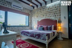 Un dormitorio con una cama y una pared de ladrillo. en StayVista at Ivycrest Estate, en Dehradun