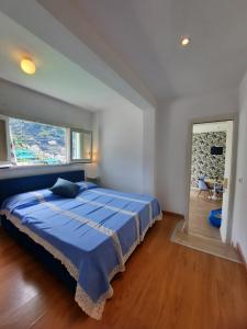 - une chambre avec un grand lit bleu et une grande fenêtre dans l'établissement Candy Candy holiday house, à Minori