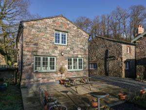 ein Steinhaus mit einem Picknicktisch davor in der Unterkunft The Barn in Seascale