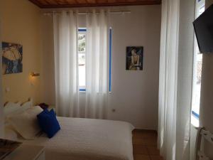 a bedroom with a bed with white curtains and a window at Ippokampos in Hydra