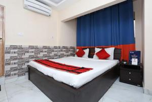 1 dormitorio con 1 cama con cortinas rojas y azules en Goroomgo White Palace Hotel & Resort New Alipore Kolkata - Fully Air Conditioned en Calcuta