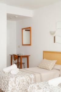 2 camas en una habitación con espejo y mesa en Hotel Santa Faz, en Benidorm