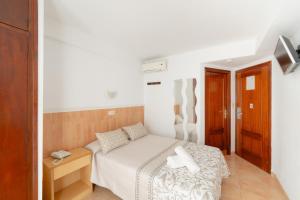 Un pequeño dormitorio con una cama blanca en una habitación en Hotel Santa Faz, en Benidorm