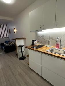 a kitchen with white cabinets and a sink at Cosy House à 9 mins RER A et 35 mins de Paris in Poissy