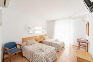 a room with two beds and a chair and a table at Hotel Santa Faz TRG in Benidorm
