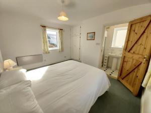 um quarto com uma grande cama branca e uma casa de banho em No3 Ballyconneely Cottage em Ballyconneely
