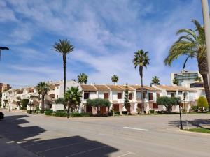 Une rangée de maisons dans une rue bordée de palmiers dans l'établissement Apartamentos Aldeas de Taray V.v., à La Manga del Mar Meno