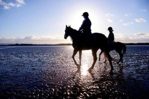 two people are riding horses on the beach at No3 Ballyconneely Cottage in Ballyconneely
