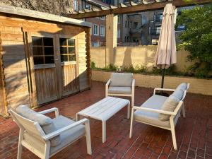 eine Terrasse mit Stühlen, einem Tisch und einem Sonnenschirm in der Unterkunft Centraal gelegen gezellig verblijf met groot terras in Ostende