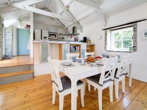 a kitchen and dining room with a white table and chairs at Stone Barn in Camelford