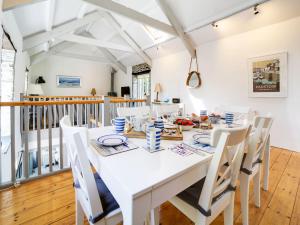 a white dining room with a white table and chairs at Stone Barn in Camelford