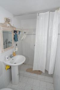 uma casa de banho com uma cortina de chuveiro branca e um lavatório. em MARKOS' HOUSE em Agiassos