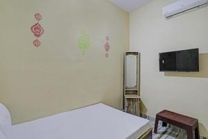 SPOT ON SKP Hotel في Chimur: غرفة بها سرير وتلفزيون على الحائط