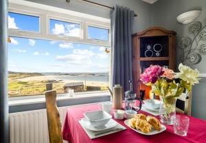 a table with a vase of flowers and a view of the ocean at Glassillaun Beach House in Renvyle