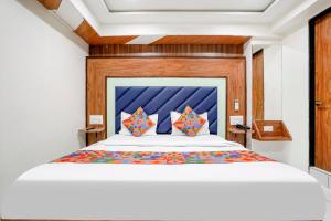 een slaapkamer met een groot bed met een blauw hoofdeinde bij FabExpress Royal Bird in Ahmedabad