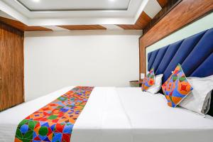 een slaapkamer met een wit bed met een blauw hoofdeinde bij FabExpress Royal Bird in Ahmedabad