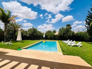 a swimming pool with lawn chairs and an umbrella at Entire villa with private pool in Marrakech in Marrakesh
