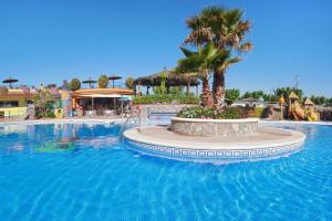 a large swimming pool in a resort with a palm tree at Kampaoh Blanes in Blanes