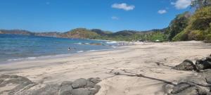 a sandy beach with people swimming in the water at Villa PRAGA Beach House in Playa Grande