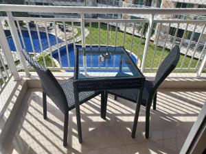 2 sillas y una mesa de cristal en el balcón en Apartamento Confortável - Porto das Dunas - Perto do Beach Park en Aquiraz