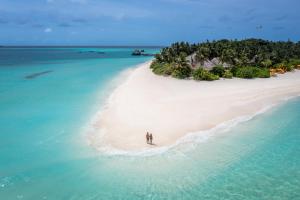 two people standing on a beach in the ocean at Angsana Velavaru - All inclusive SELECT in Dhaalu Atoll