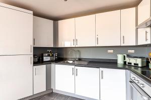 eine weiße Küche mit weißen Schränken und Geräten in der Unterkunft Urban and Stylish Apartment in London