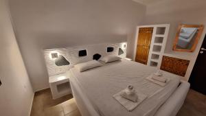 1 dormitorio con 1 cama blanca y 2 toallas en Chryssa Bungalows, en Ándros