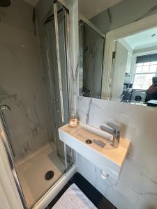 La salle de bains est pourvue d'un lavabo et d'une douche. dans l'établissement Apartments in the Heart of High Street Kensington, à Londres