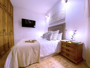 a bedroom with a white bed with a dresser and a tv at Tropicalidays Arona Mountain Scape in Arona