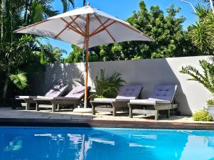 een parasol en stoelen naast een zwembad bij Leopard Corner Lodge in St Lucia