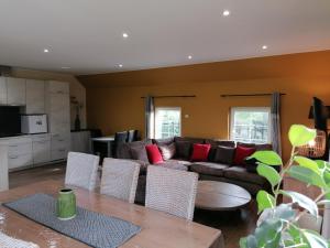 ein Wohnzimmer mit einem Sofa und einem Tisch in der Unterkunft Maison du Pré à 2 pas de Pairi Daiza in Brugelette