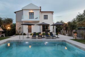 a house with a swimming pool with chairs and umbrellas at Villa Nineta in Tavronitis
