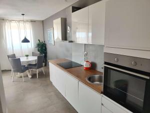Lara's apartment في زادار: مطبخ بدولاب بيضاء ومغسلة وطاولة