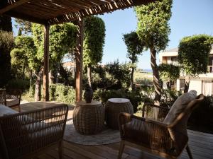 普拉諾斯的住宿－Sentiero Iconic Villa, a Serene Retreat, By ThinkVilla，露台配有椅子和桌子,甲板上配有桌子