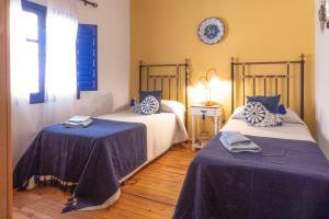 a bedroom with two beds and a clock on the wall at Cortijo Fernando in Frigiliana +8 photos