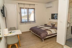 a bedroom with a bed and a desk and a window at Apartments Caric in Hvar