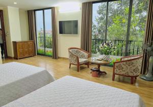 a hotel room with two beds and a table and chairs at Thu Ha Hotel in Uông Bí