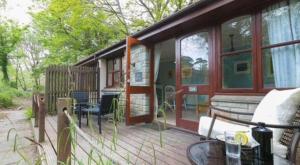 a house with a deck with a couch and a table at Rebels Retreat - 2-Bed Chalet nr St Ives & Hayle in St Ives