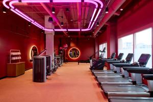 un gimnasio con filas de bicicletas estáticas y luces rosas en Downright Austin, A Renaissance Hotel, en Austin