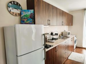 a kitchen with a white refrigerator and wooden cabinets at Апартамент Sunny home in Chernomorets