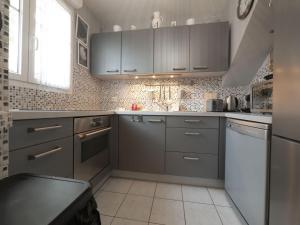 eine Küche mit Küchengeräten aus Edelstahl und grauen Schränken in der Unterkunft TEA&CHILL- Les Bluets - house with 2 terraces in Noisy-le-Sec
