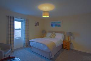 a bedroom with a bed and a chair and a window at The Harbour Inn in Garlieston