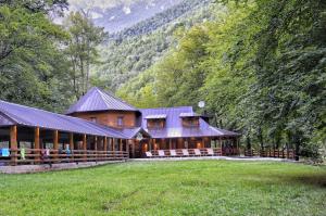 a large wooden house in the middle of a field at Hotel Porto Tara in Žabljak