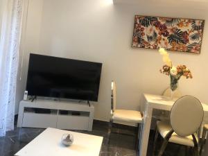 ein Wohnzimmer mit einem TV, einem Tisch und Stühlen in der Unterkunft 3 pièces 2 SDB centre de Cannes in Cannes