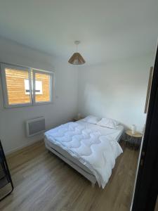 a white bedroom with a bed and a window at Les Chalets du Mancel : Chalet Lulu - Bouleries Jump - 24h du Mans in Parence