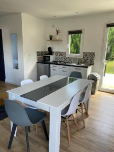 a kitchen with a white table and chairs at Les Chalets du Mancel : Chalet Lulu - Bouleries Jump - 24h du Mans in Parence +2 photos